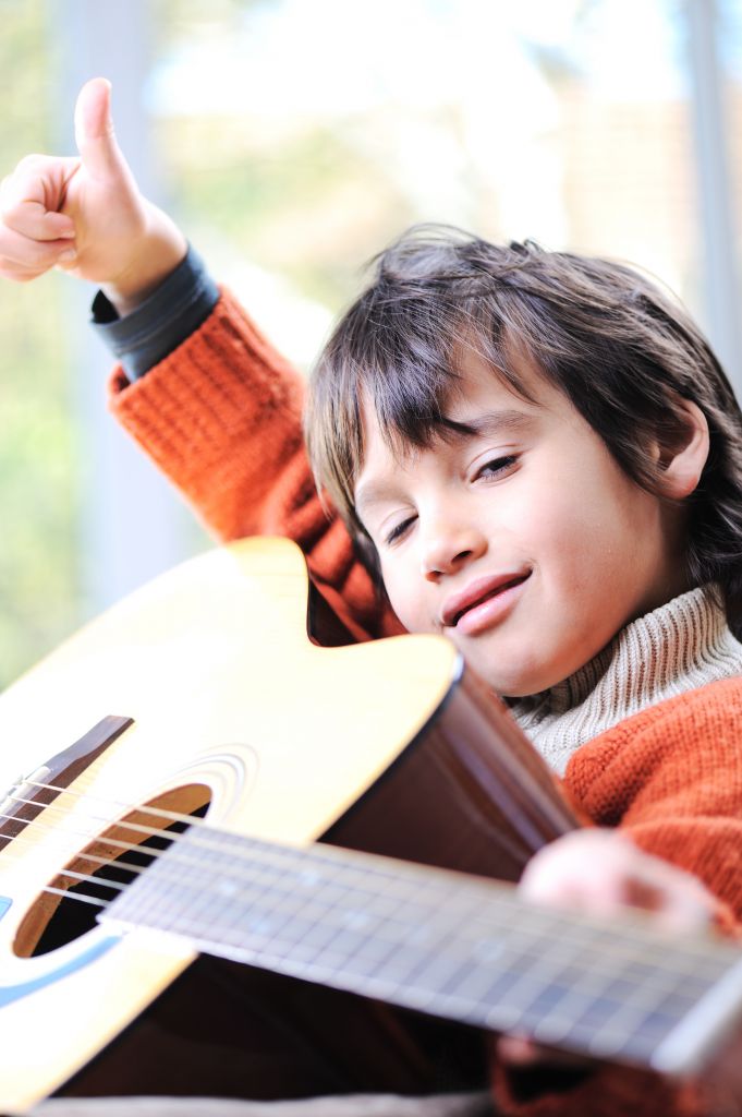 Smiling boy plays the guitar